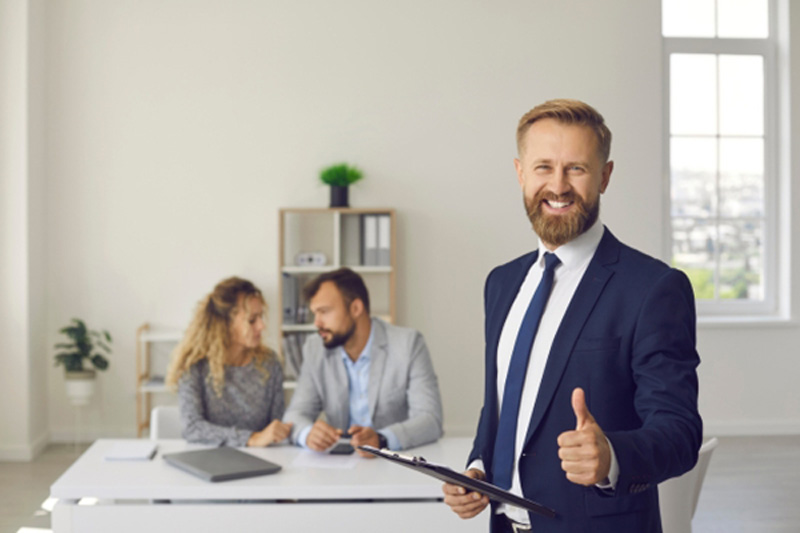 Immobilienmakler Ginnheim steht mit Daumen nach oben vor einem Paar